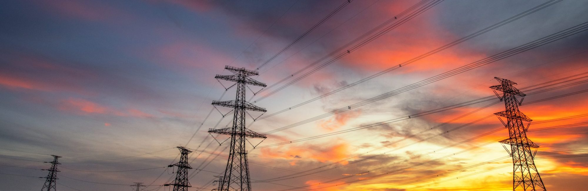 electricity transmission pylon silhouetted against blue sky at dusk